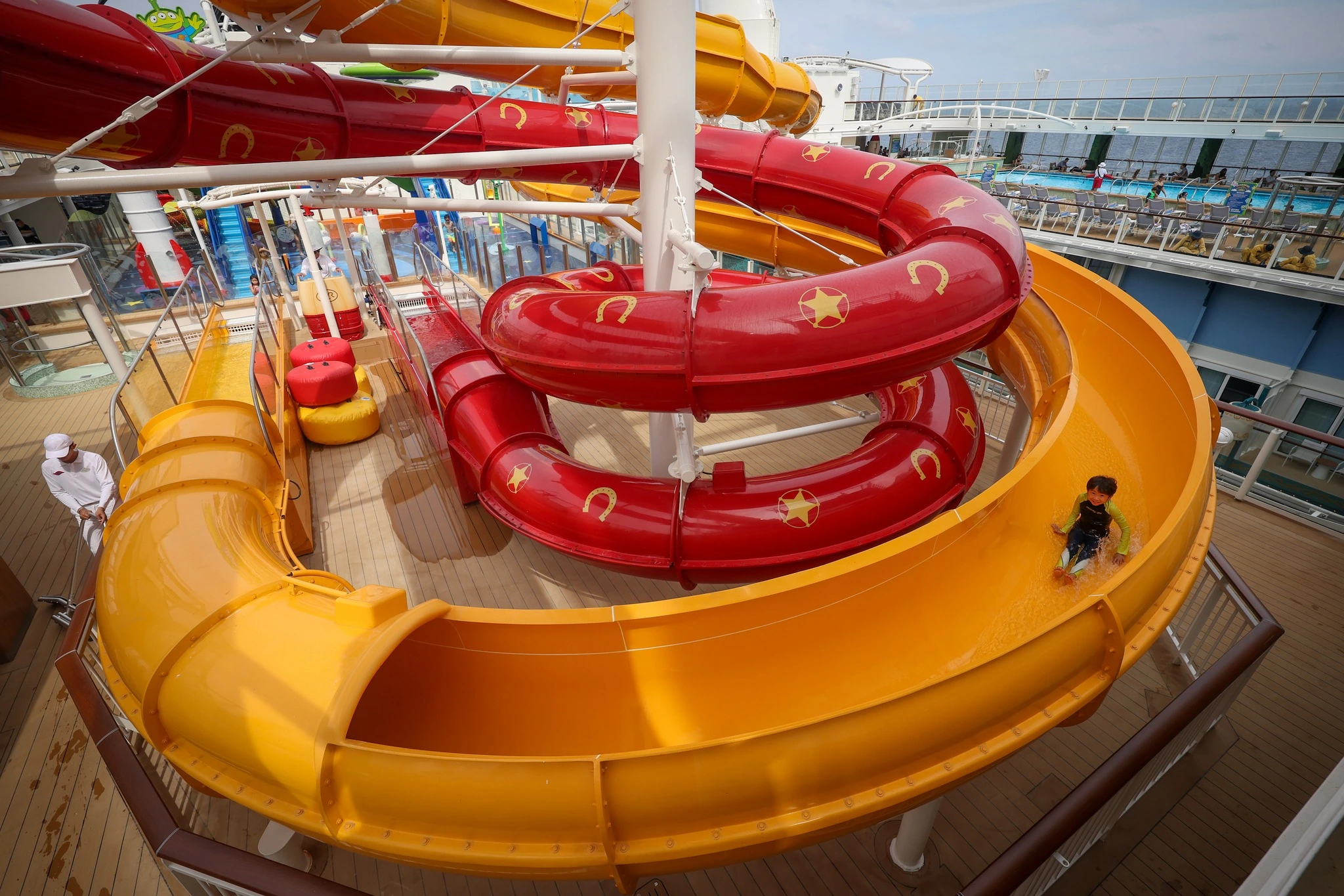 Toy Story Place red and yellow twisting water slides close-up with child sliding down on Disney Adventure cruise