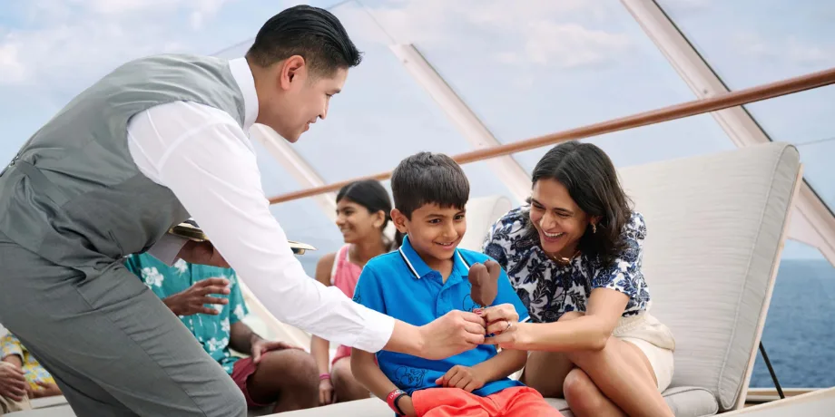 Crew member serves a Mickey ice cream bar to a child on the pool deck during a Disney cruise.