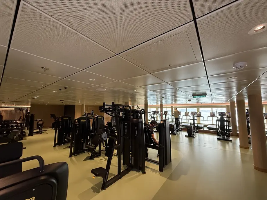 Fitness centre on Deck 10 of the Disney Adventure — weight machines, cardio equipment, and ocean-view windows